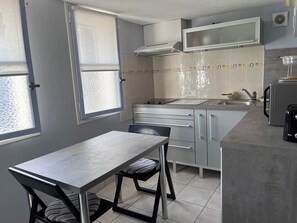 A modern kitchen with a dining table, chairs, a microwave, and a sink. - A stopover in the heart of the Basque Country (Halsou)