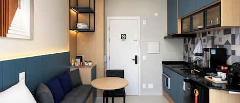 Habitació d'hotel petita amb llit, sofà, taula de dinar, cuineta i bany.