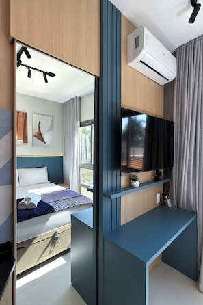 Een moderne hotelkamer met een bed, een tv aan de muur en een airconditioning.