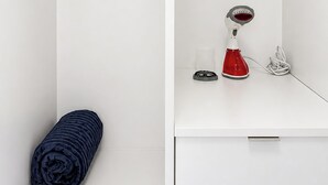 Een badkamer met een douche, een handdoek, een haardroger en een beker.
