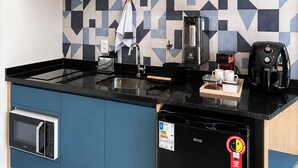Een keuken met blauwe kastjes, een zwart aanrecht, een koffieapparaat en een magnetron.