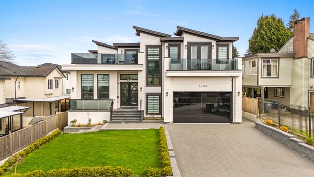 Une maison moderne à deux étages, dotée d’un garage, d’une pelouse bien entretenue et surplombant un ciel dégagé.
