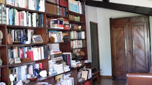 Ein Zimmer mit einem großen Bücherregal voller Bücher, einer Holztür und einer Bank.
