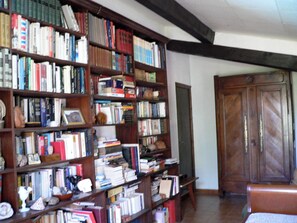 Ein Zimmer mit einem großen Bücherregal voller Bücher, einer Holztür und einer Bank.