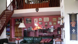 Ein Wohnzimmer mit Treppe, einem grünen Ledersofa, einem Holztisch und verschiedenen gerahmten Bildern an der Wand.