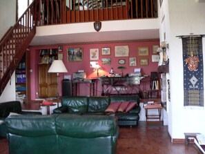 Ein Wohnzimmer mit Treppe, einem grünen Ledersofa, einem Holztisch und verschiedenen gerahmten Bildern an der Wand.