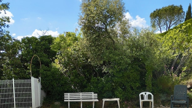 Ein Schwimmbecken mit Zaun, Bänken und Bäumen im Hintergrund.