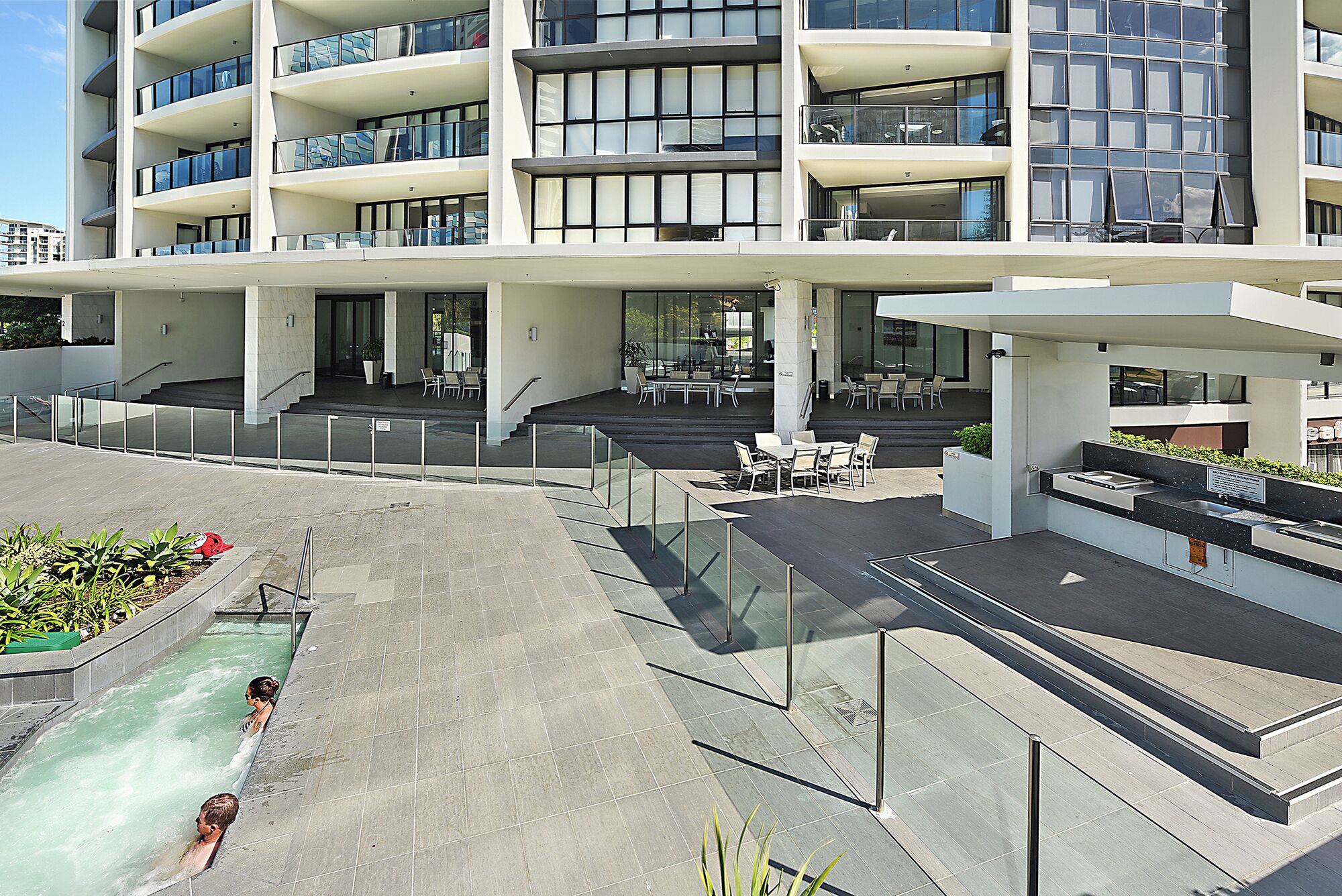 Un bâtiment moderne doté de nombreux balcons, d’espaces de détente en plein air et d’une piscine.