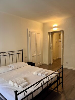 A bedroom with a bed, a wardrobe, and a bathroom visible through an open door. - Charming Cozy flat in the Heart of Porta Venezia (Milan)