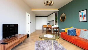 A modern living room with a TV, sofa, coffee table, and dining area. - Luxury Soho House Residence – Gym, Pool, Cinema & Prime London Living (London)