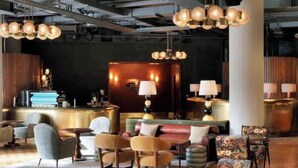 A lobby with a reception desk, seating area, and hanging spherical light fixtures. - Luxury Soho House Residence – Gym, Pool, Cinema & Prime London Living (London)