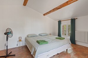 A bedroom with a bed, a standing fan, a radiator, and a window with curtains. - Holiday Home 'Grand Mas Provencal - 9 Ch - 18 Per' with Mountain View, Private Pool and Wi-Fi (La Farlède)