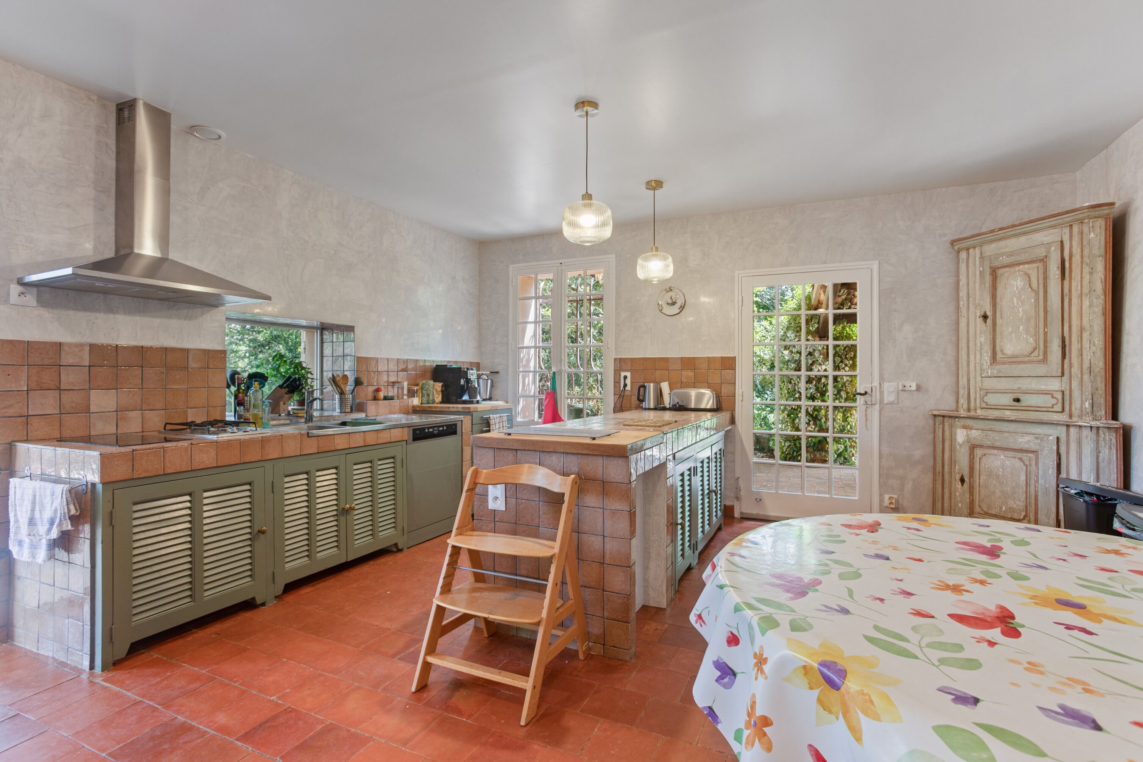 Una cocina con una isla central, un comedor con una silla y una cama con cubrecama floral.
