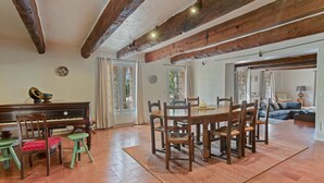Ein geräumiger Wohnbereich mit einem Holzespeisetisch, Stühlen, einem Klavier und einem Sofa.