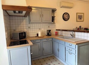 A kitchen with a microwave, stove, sink, and cabinets. - Gîte la villa jane (Saint-Laurent-la-Vernède)