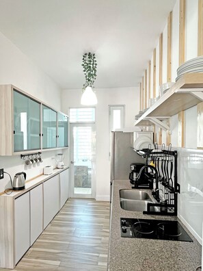 A modern kitchen with a central island, a hanging plant, and built-in shelves. - Spacious 3br Drenched with light Gem Beach Walk Loíza · Quiet & Airy (San Juan)