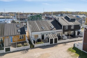 A row of modern, multi-story buildings with flat roofs, a white picket fence, and a marina in the background. - Holiday apartment in Øer Maritime Ferieby (Ebeltoft)