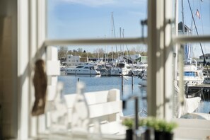 A marina with boats docked, a view through a window, and a potted plant on the windowsill. - Holiday apartment in Øer Maritime Ferieby (Ebeltoft)