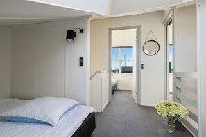 A bedroom with a bed, a nightstand, a wall-mounted lamp, a mirror, and a vase with flowers. - Holiday apartment in Øer Maritime Ferieby (Ebeltoft)