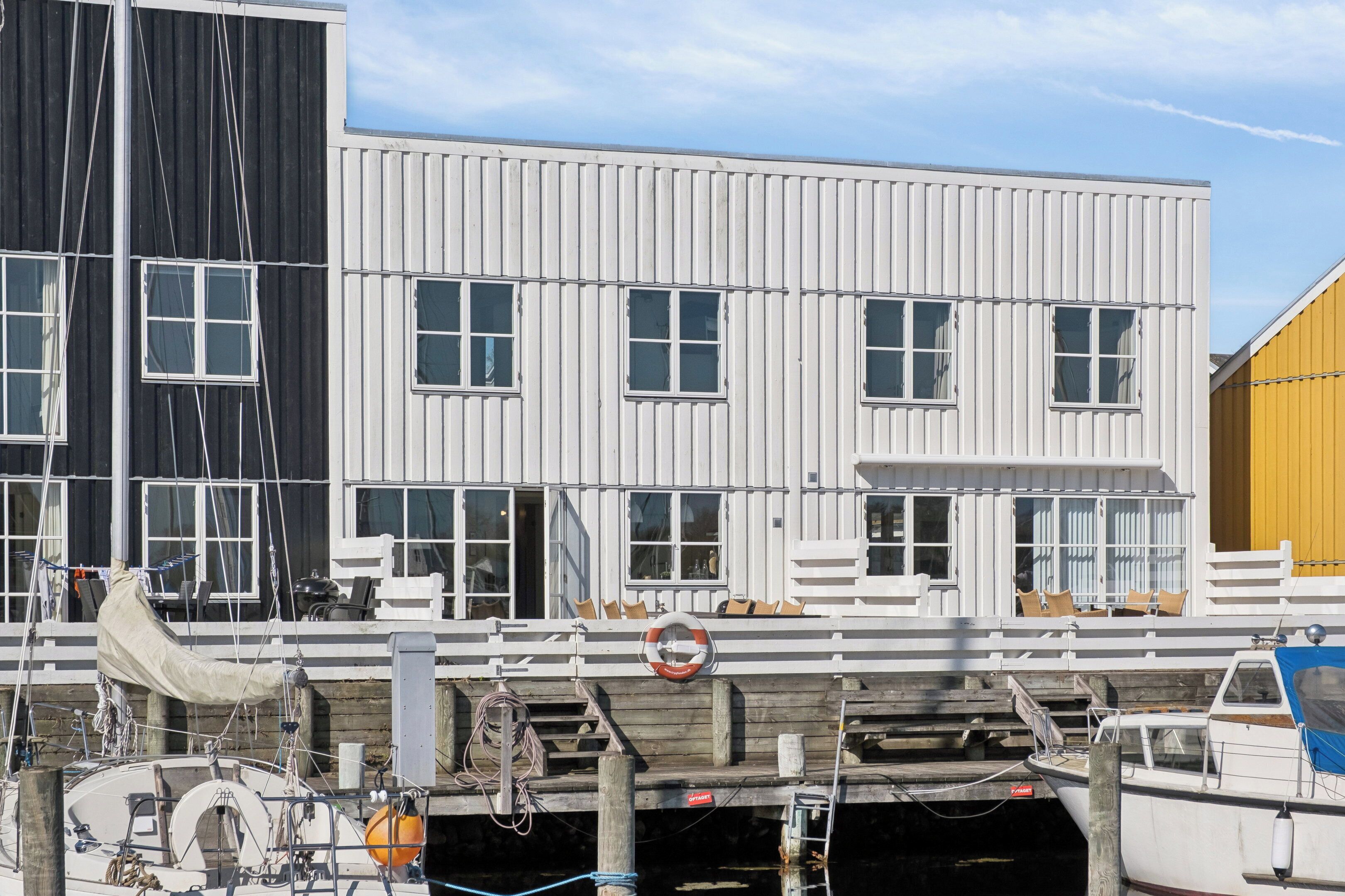 A multi-story building with large windows, a balcony with chairs, and a lifebuoy.