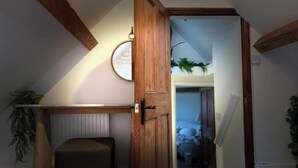 A room with a wooden door, a radiator, a plant, and a view of a staircase.