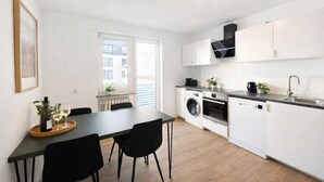 A compact kitchen with a dining table, chairs, a washing machine, an oven, and a sink. - Central living between the Rhine, old town and vineyards (Rüdesheim am Rhein)