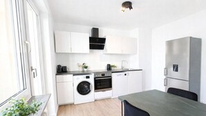 A compact kitchen with a washing machine, oven, and dishwasher, a dining area with a table and chairs, and a refrigerator. - Central living between the Rhine, old town and vineyards (Rüdesheim am Rhein)