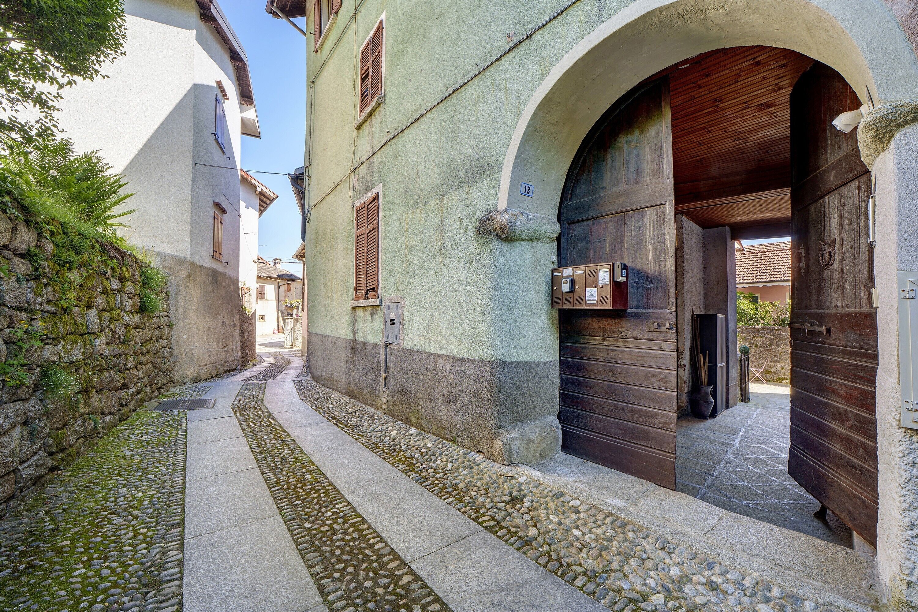 A narrow street with cobblestone pavement, stone walls, and wooden doors.