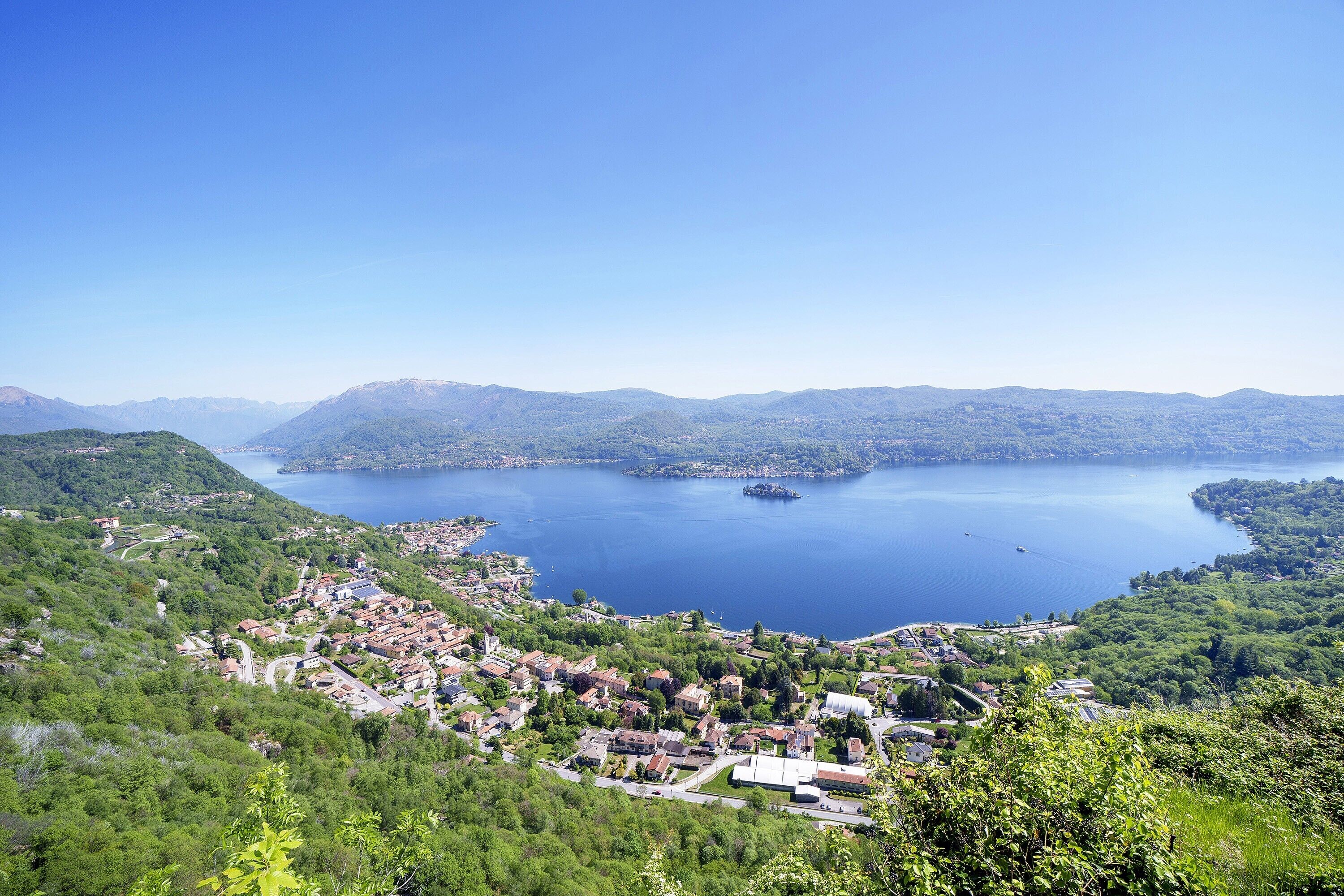 Un lac entouré de montagnes et une ville o ù l’on peut voir des bâtiments et des routes.