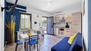 Un espacio habitable compacto con comedor, kitchenette y un sofá con cojín.