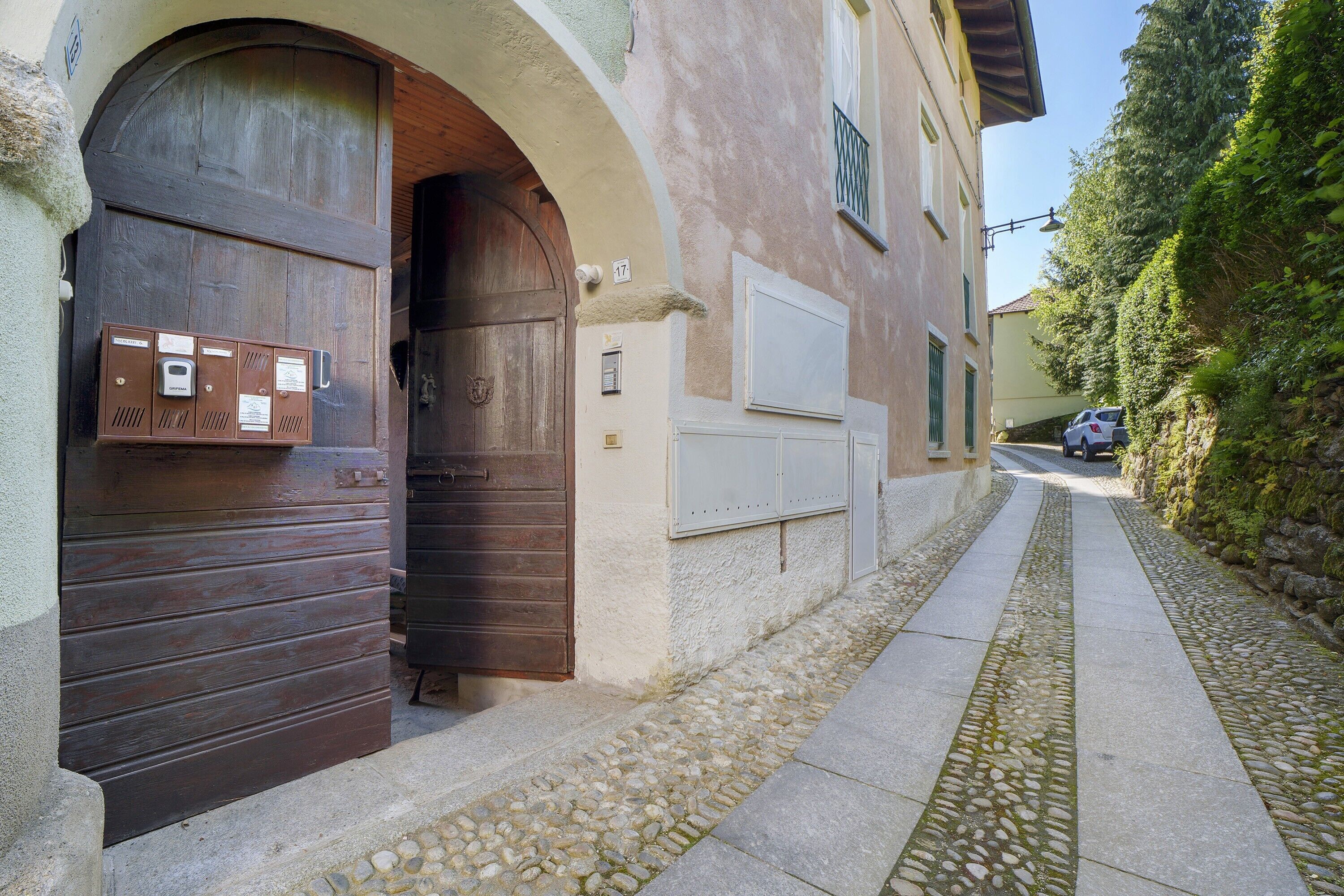 A narrow alleyway with a stone-paved path, a wooden door, and a mailbox.