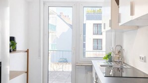 Eine moderne Küche mit Backofen, Spüle und Fenster mit Blick auf einen Balkon.
