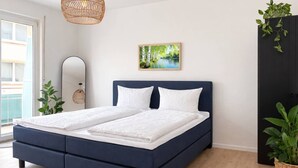 Ein modernes Schlafzimmer mit einem großen Bett, einem Schminkspiegel, einer Pendelleuchte und einem Bild an der Wand.