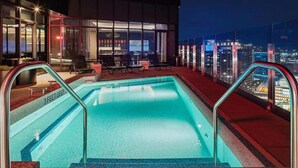 A rooftop pool with a view of the cityscape at night. - Luxury Seaport Stay | Rooftop & Pool (Boston, MA)