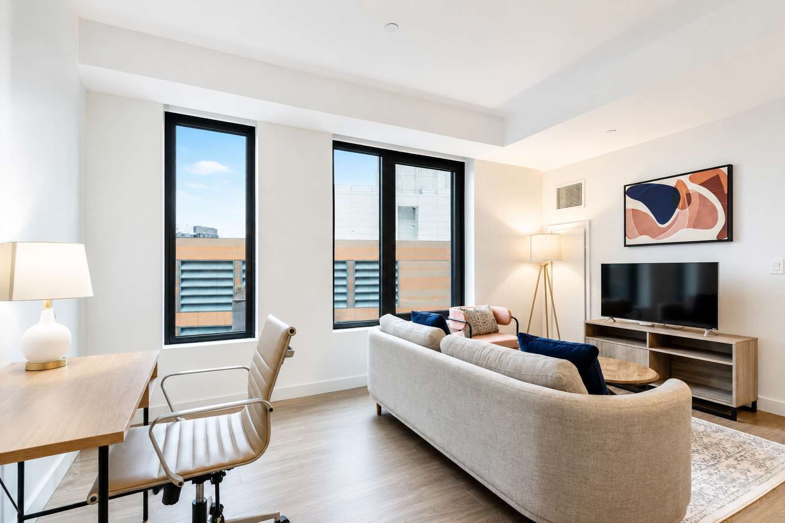 A modern living room with a sofa, a TV, a lamp, and a floor lamp.