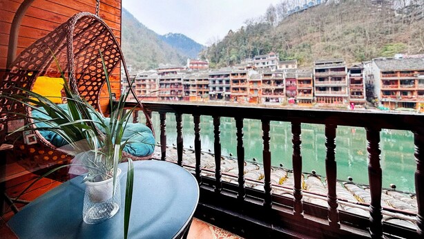 A balcony with a view of traditional buildings and a river. - Fenghuang Meomory Riverview Inn (Xiangxi)