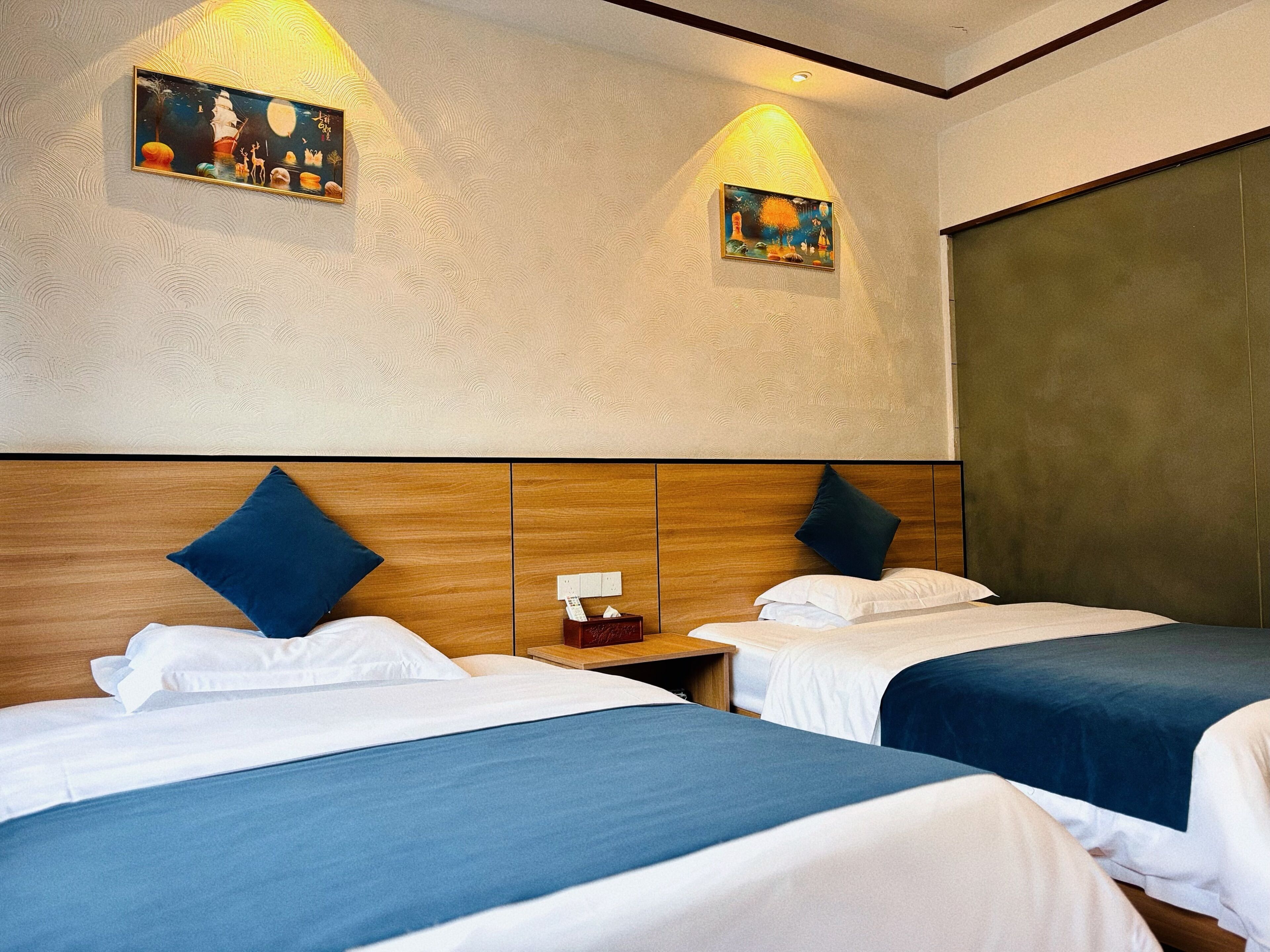 Habitación de hotel con dos camas, cabeceros de madera y dos cuadros colgados en la pared.