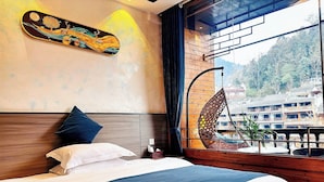 A bed with pillows, a hanging chair, and a view of buildings through a window. - Fenghuang Meomory Riverview Inn (Xiangxi)