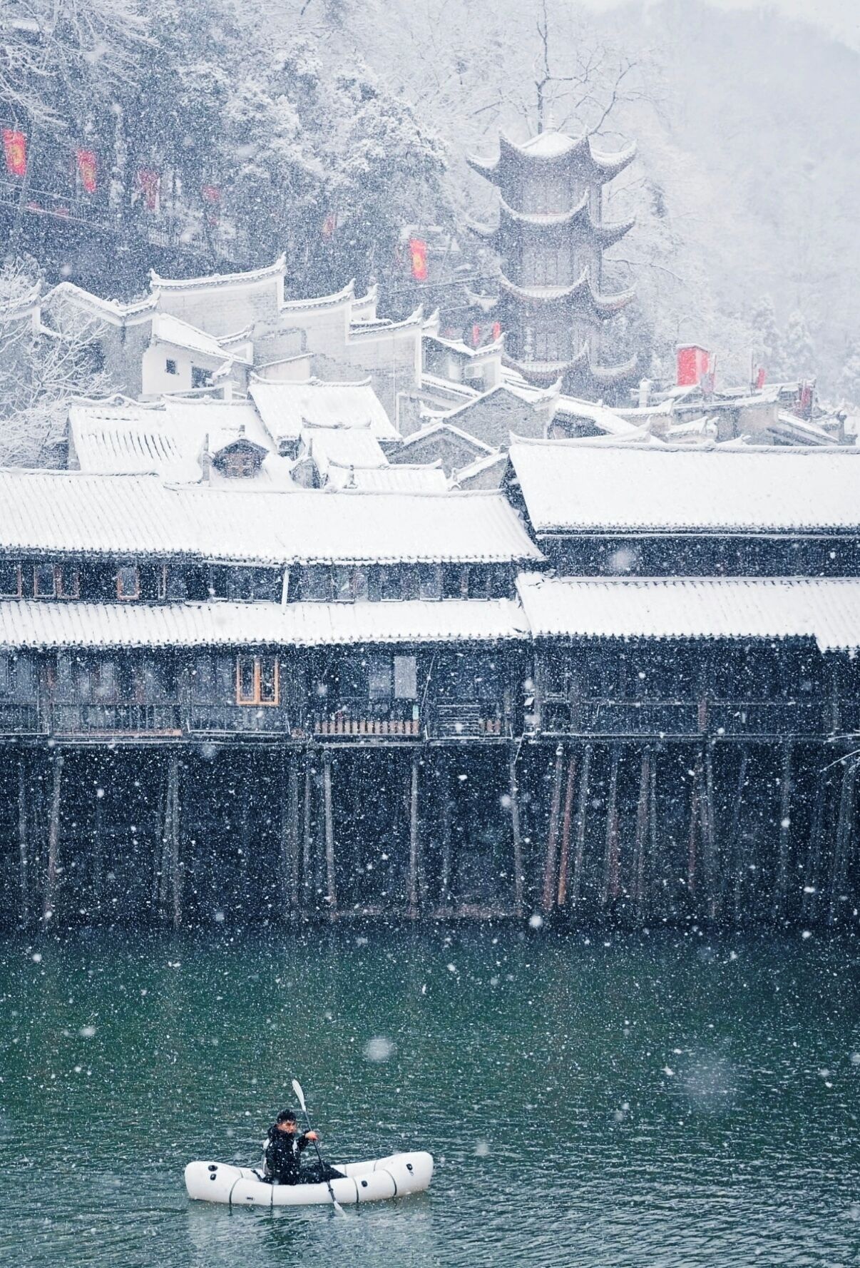A traditional building with multiple tiers and a pagoda-style roof, surrounded by snow-covered trees and structures.