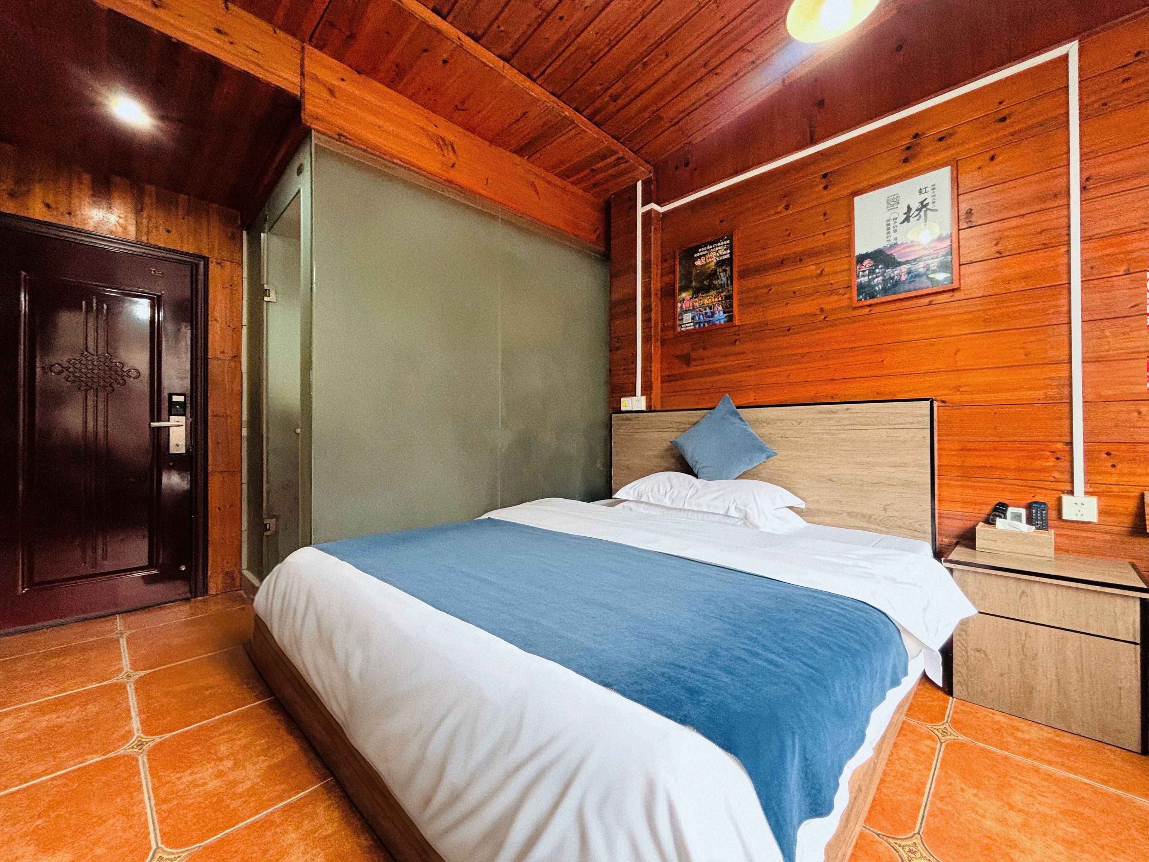 A wooden-paneled room with a bed, a nightstand, and a door.