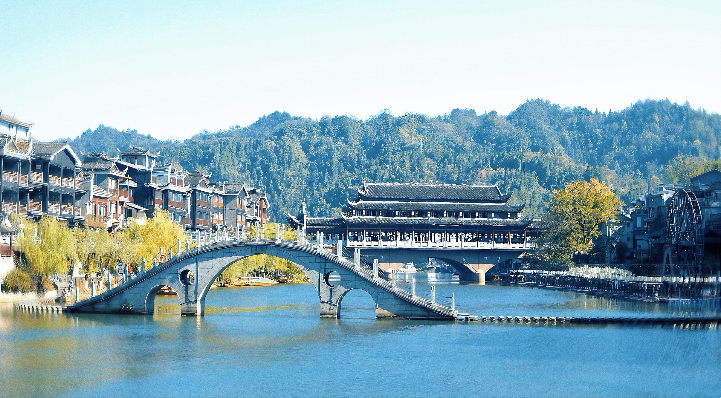 Eine traditionelle Brücke über einem Fluss, im Hintergrund ein historisches Gebäude.