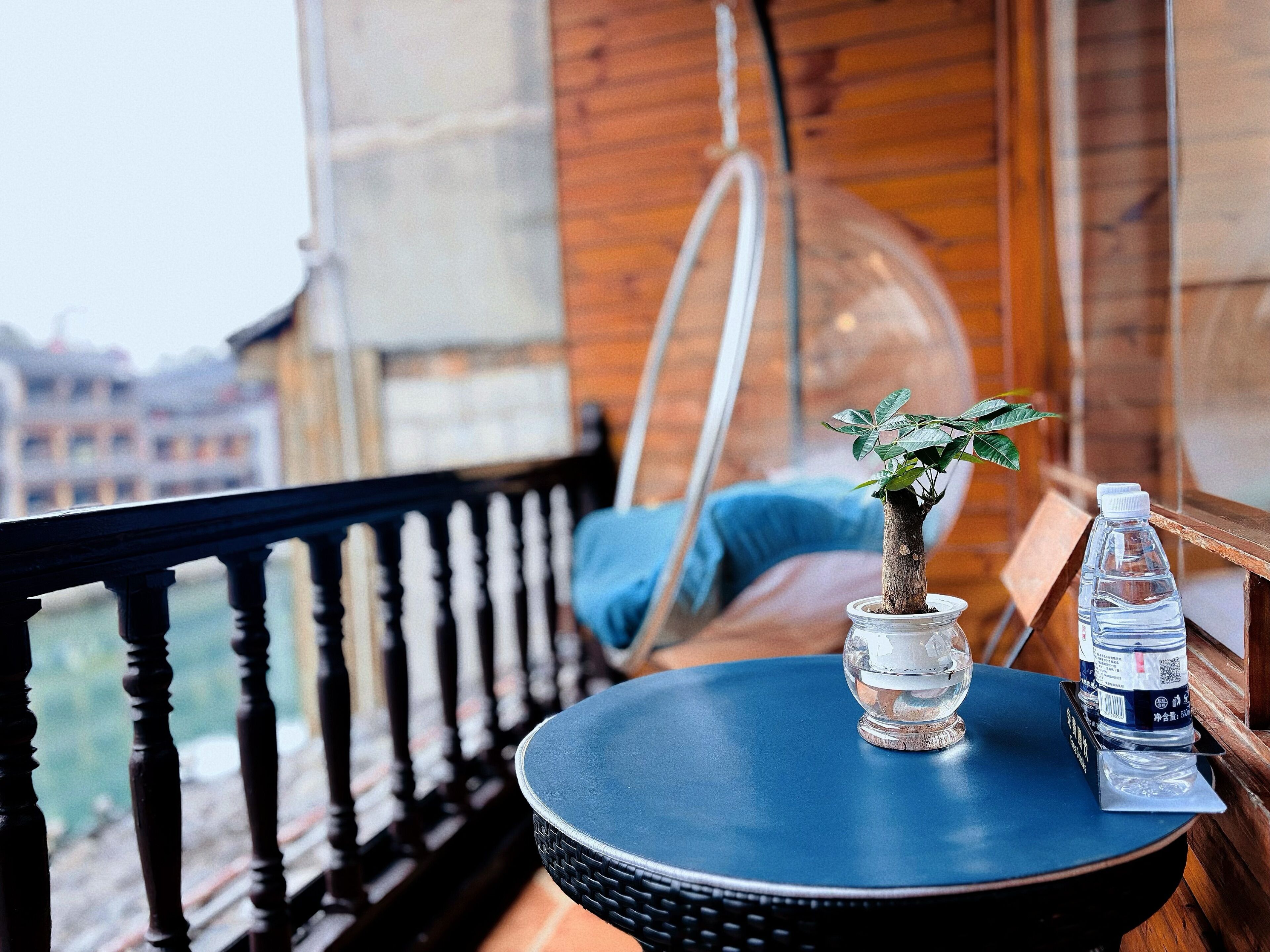 A balcony with a small table, a potted plant, and a water bottle.