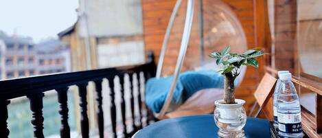 A balcony with a small table, a potted plant, and a water bottle.
