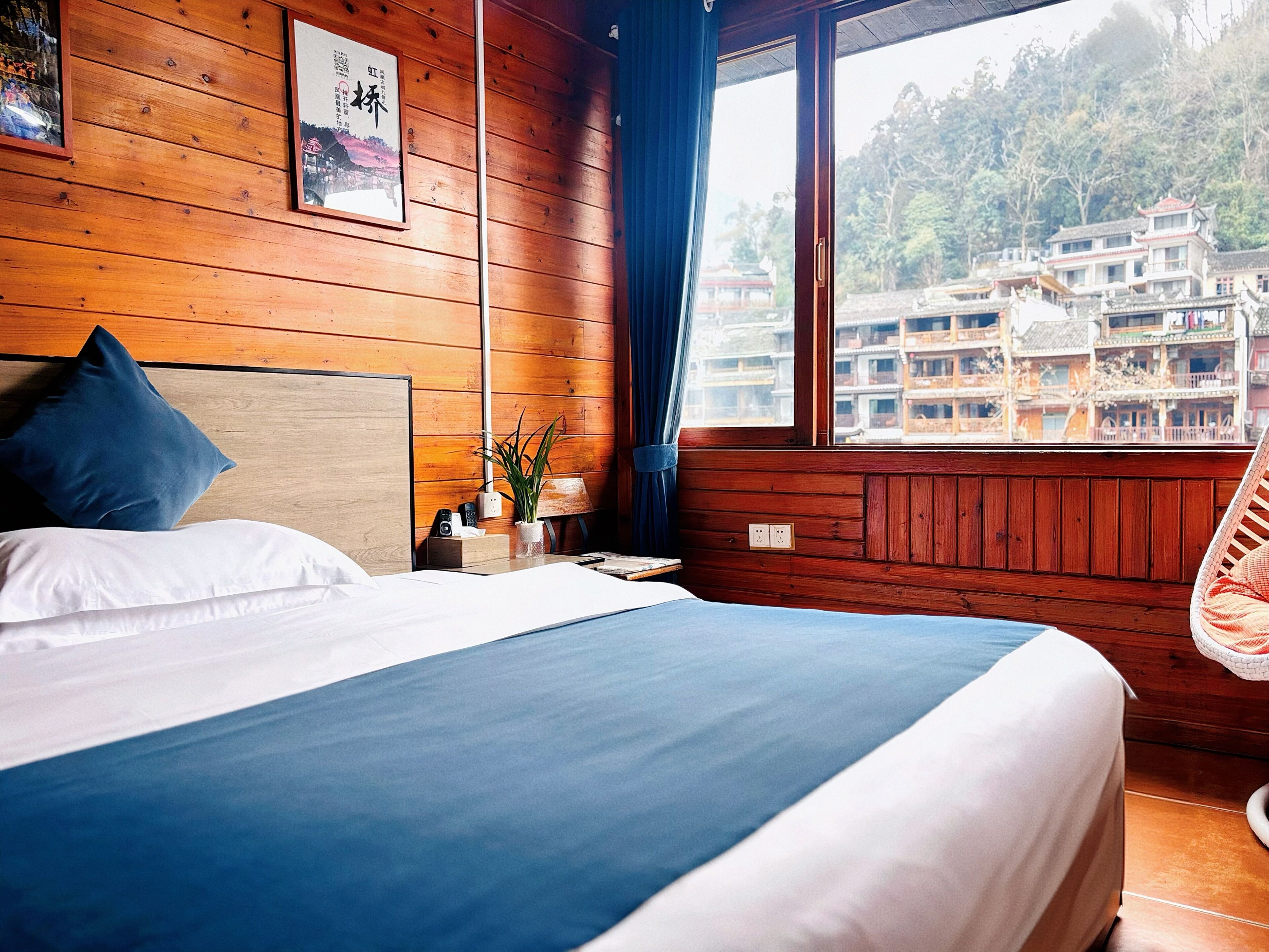 A wooden room with a bed, a window, and a view of buildings.