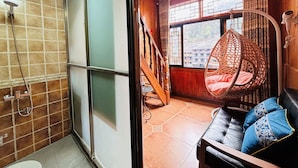 A bathroom with a shower, a toilet, and a sink. There is a wooden staircase leading to a balcony with a hanging chair and a sofa. - Fenghuang Meomory Riverview Inn (Xiangxi)