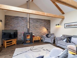 A living room with a stone wall, a fireplace, a television, and two sofas. - Cider Press Cottage (Torpoint)