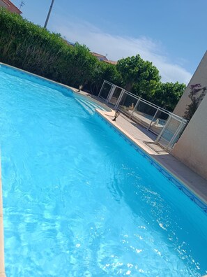 A swimming pool with clear water, surrounded by greenery and a building with a tiled roof. - St Cyprien Magnificent Villa with Swimming Pool (Saint-Cyprien)