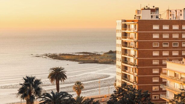 Un edificio de gran altura con varios balcones que dan a una playa.