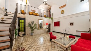 Un amplio espacio de sala con una escalera, una estatua de perro, muebles rojos y una mesa de centro de vidrio.