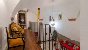 Un pasillo con suelo de madera, un sofá rojo y un sillón amarillo.